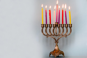 Eighth day of Hanukkah with burning Hanukkah colorful candles in Menorah (traditional Candelabra) .Chanukkah-jewish holiday. Each night, another candle is added. Copy space for text.