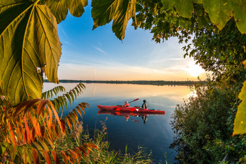 Kayaking on a blue lake at beautiful sunset
