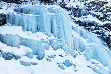 Huge icicles. Large blocks of frozen water coming from the mountains. Blue ice background. 