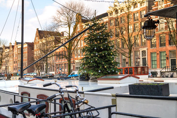 Christmas cityscape - view of houseboat with Christmas tree in the old district of Amsterdam on the...