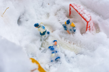 Children's board game of hockey was left in the open air in the yard and covered with the first snow. Toy hockey players under a snow.