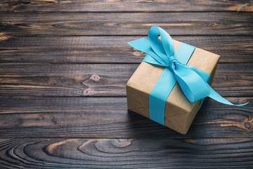 paper gift box with blue ribbon on dark wood background. top view vintage, toned with copy space