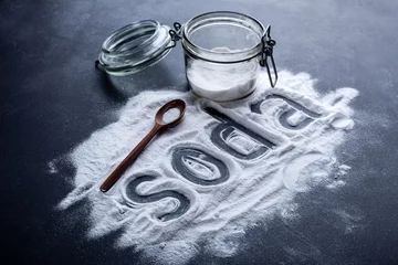 Poster baking soda scattered from a glass jar on a dark background © Sunny Forest