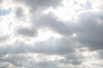 Sun hiding behind the fluffy clouds. Sunlight coming through clouds