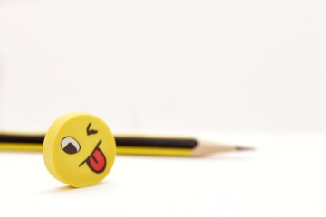 cheerful mischievous yellow face and pencil on a light background