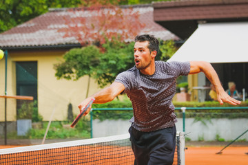 Junger Tennisspieler streckt sich um einen Rückhandvolley zu spielen