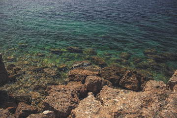vivid green water surface with small waves of Mediterranean sea shore line and rocks nature outdoor landscape  