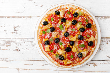 Pizza with tomatoes, mozzarella cheese, olives, corn and basil. Traditional italian cuisine. Top view