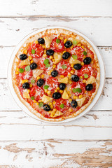 Pizza with tomatoes, mozzarella cheese, olives, corn and basil. Traditional italian cuisine. Top view