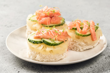 Bruschetta toast of white bread with slices of pineapple cucumber fish salmon fresh green sprouts