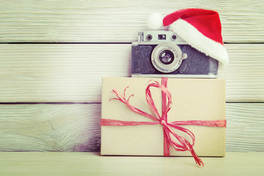 Vintage camera in santa hat and gift box over.