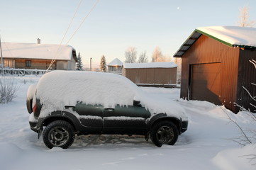 SUV covered with snow is in the yard