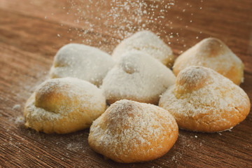 cottage cheese biscuits in breadcrumbs of powdered sugar on a wooden background