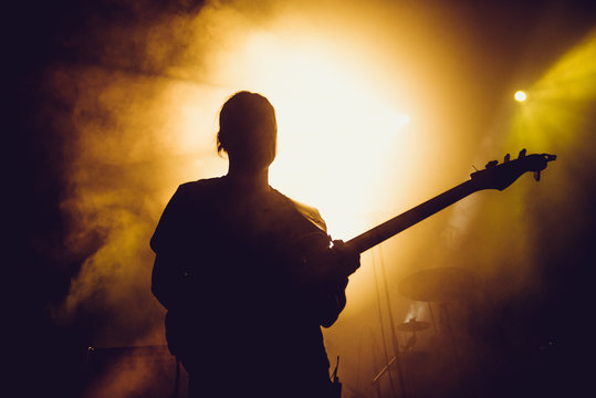 Guitarist silhouette on a stage in a smoke and backlights playing rock music