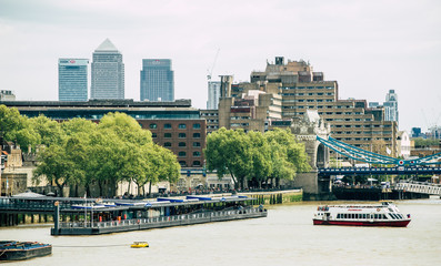 A boat next to the Tower Bridge pier with Canary Wharf in the background