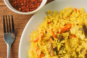 Uzbek pilaf with lamb, spices and seasonings, decorated with lettuce leaves on a wooden background