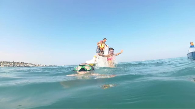 famile jumping from catamaran to sea and looking at camera, outdoors