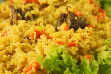 Uzbek pilaf with lamb, spices and seasonings, decorated with lettuce leaves on a wooden background