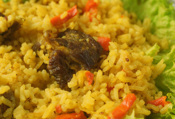 Uzbek pilaf with lamb, spices and seasonings, decorated with lettuce leaves on a wooden background