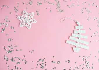 Christmas toy with text We wish you a Merry Christmas in pastel pink background with silver glitter, party concept, top view