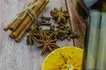 Hot mulled wine drink with lemon, apple, cinnamon, anise and other spices in a glass cup between fir tree branches on wooden cutting board