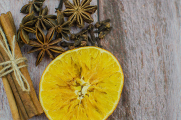 Hot mulled wine drink with lemon, apple, cinnamon, anise and other spices in a glass cup between fir tree branches on wooden cutting board