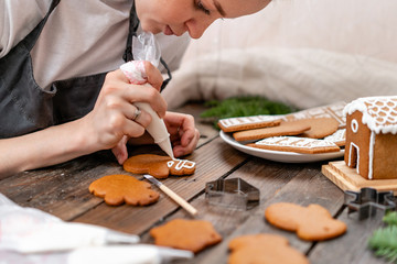 A young girl decorates ginger cookies Christmas winter mornin