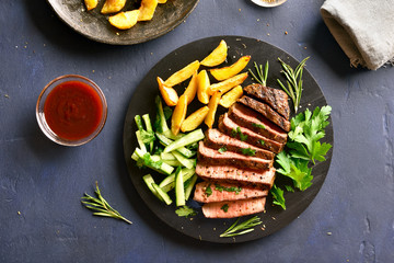 Beef steak with potato wedges and cucumber salad