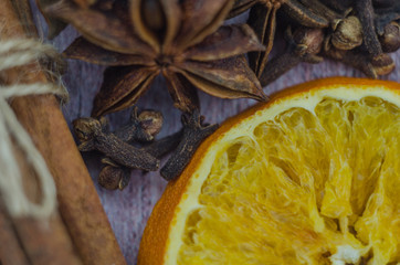 Hot mulled wine drink with lemon, apple, cinnamon, anise and other spices in a glass cup between fir tree branches on wooden cutting board