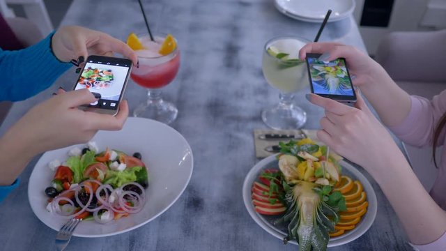 slimming food, girlfriends on smartphone taking pictures of vegetable and fruit salad for social media during healthy brunch in cafe close up