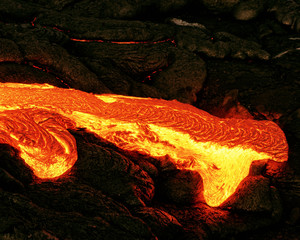 Hot magma escapes from an earth column as part of an active lava flow, the glowing lava slowly...