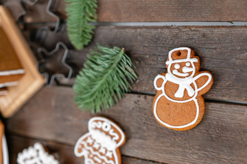 Cookies in the form of snowman Christmas winter morning. Woman draws Icing on honey gingerbread cookies. Wooden brown table. copy space.