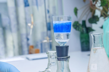 a chemist holds a glass test tube in his hand, overflows a liquid solution, conducts an analysis...