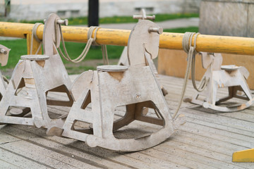 little swing for babies with the shape of a horse, wooden seesaw detail, in a garden