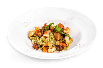 Plate of tasty seafood tagliatelle pasta with salmon and shrimps isolated at white background.
