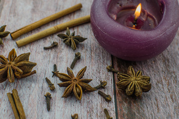 Hot mulled wine drink with lemon, apple, cinnamon, anise and other spices in a glass cup between fir tree branches on wooden cutting board