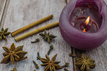 Hot mulled wine drink with lemon, apple, cinnamon, anise and other spices in a glass cup between fir tree branches on wooden cutting board