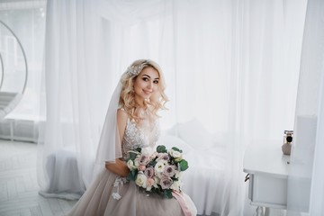Beautiful blonde bride in a modern dress posing in the Studio. Morning newlyweds.
