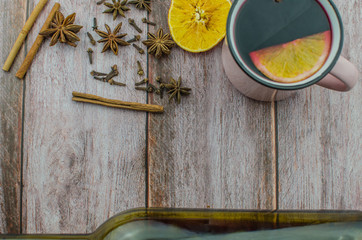 Hot mulled wine drink with lemon, apple, cinnamon, anise and other spices in a glass cup between...