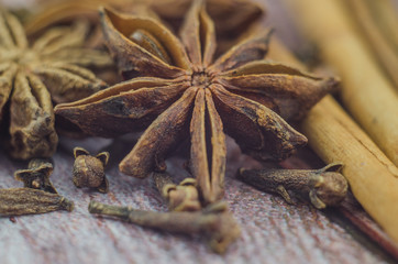 Hot mulled wine drink with lemon, apple, cinnamon, anise and other spices in a glass cup between fir tree branches on wooden cutting board