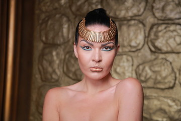 Pretty Tan Brunette Posing. Egypt Style Rich Luxury Woman With Jewellery on Golden Background.