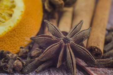 Hot mulled wine drink with lemon, apple, cinnamon, anise and other spices in a glass cup between fir tree branches on wooden cutting board