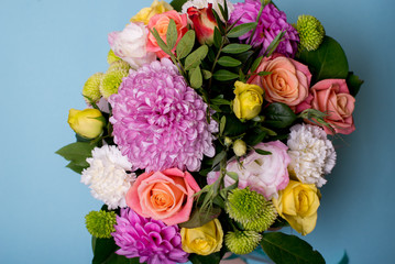 beautiful floral arrangement, pink and yellow rose, pink eustoma, green and pink chrysanthemum, white carnation, pink dahlia on a blue, turquoise background with space for text.