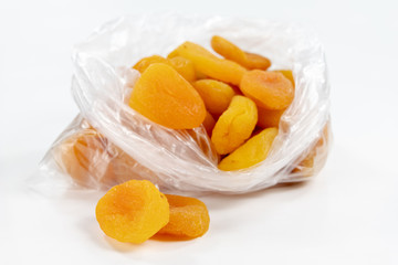 Tasty dried apricots in a white bowl. Treats for cakes on the kitchen table.