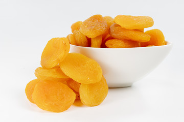 Tasty dried apricots in a white bowl. Treats for cakes on the kitchen table.