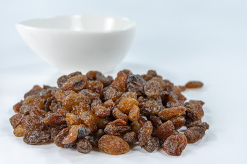 Tasty raisins in a white bowl. Treats for cakes on the kitchen table.