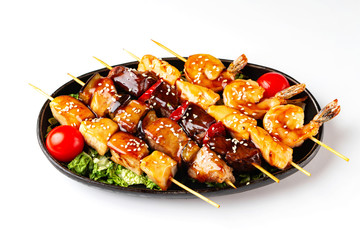 Closeup plate of grilled barbeque set of beef, porkm chicken, salmon and shrimps sticks isolated at white background.