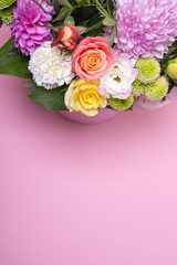 beautiful floral arrangement in the box, pink and yellow rose, pink eustoma, green and pink chrysanthemum, white carnation, pink dahlia on pink background with space for text.