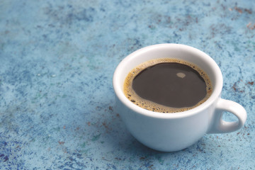 white cup with coffee on the table. horizontal view. place for text. Abstract background.