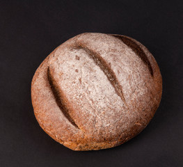 Булка черного хлеба на черном фоне